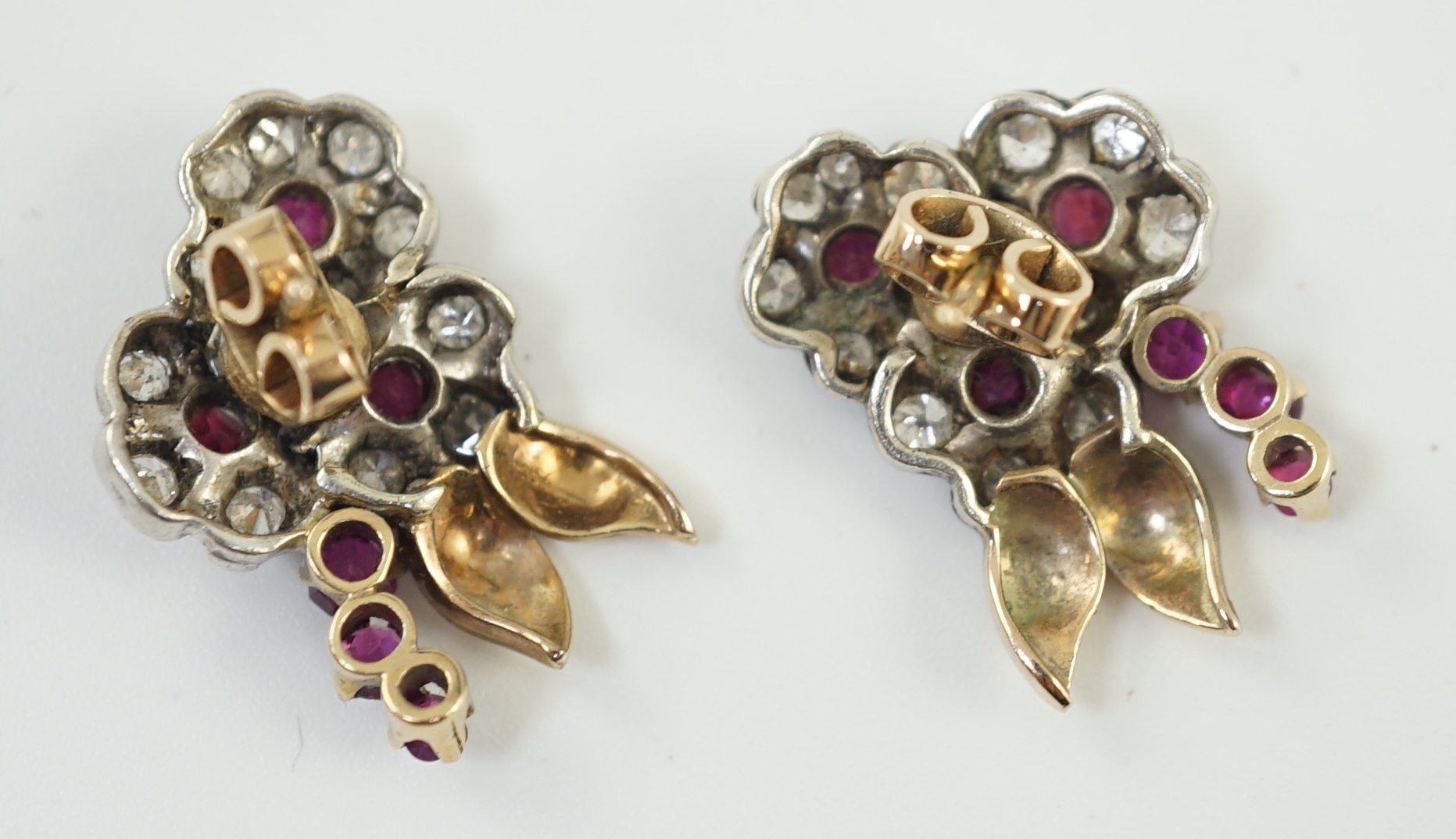 A pair of 1950's gold ruby and diamond set triple flower head cluster earrings